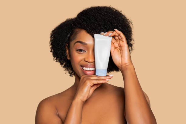 Smiling woman holding a skincare tube in front of her face